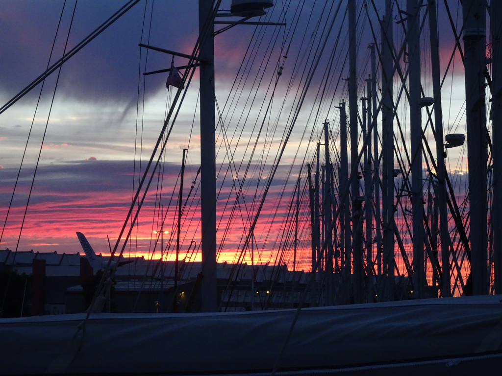 Couché de soleil à travers les nombreux mâts des bateaux. Ciel rouge.