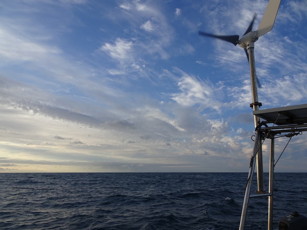 Mer calme et ciel couchant bleu zebré de nuage. Éolienne de 3Gouttes en mouvement