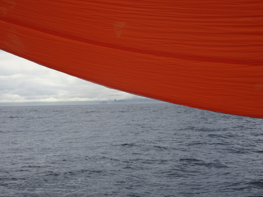 La terre est visible sous le spi orange vif de 3Gouttes
